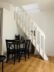 a dining room table with two chairs and a staircase at Joli duplex in Dijon