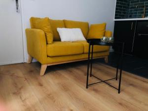 a yellow couch with a side table in a living room at Joli duplex in Dijon