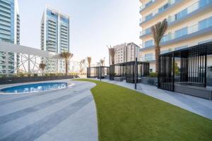 un grand bâtiment avec une pelouse devant lui dans l'établissement HiGuests - Bella Rose Studio With Stunning Desert Views, à Dubaï