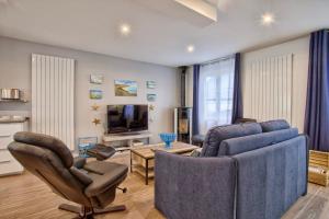 a living room with a couch and chairs and a tv at La Casa Bella - Calm and cosy house by the sea in Ouistreham