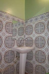 uma casa de banho com um lavatório e uma parede em azulejo em Au jardin de Tamnougalt em Agdz
