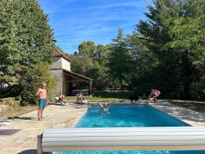 um grupo de pessoas sentadas ao redor de uma piscina em La Rossignolerie - La familiale Vigneronne em Chouzy-sur-Cisse