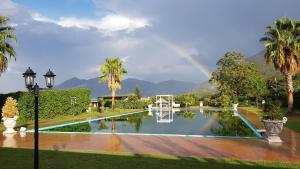 einen Regenbogen über einem Garten mit Pool und Palmen in der Unterkunft Villa Nasti Luxury Bed Taurasi Room in Nocera Inferiore