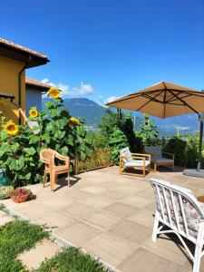 - une terrasse avec 2 chaises et un parasol dans l'établissement I girasoli, à Sanzeno