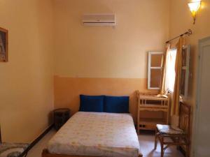 a bedroom with a bed and a table and a window at Au jardin de Tamnougalt in Agdz