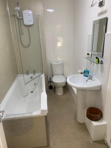 a bathroom with a toilet and a tub and a sink at The Dock Inn in Penzance