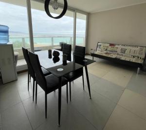 a dining room with a table and chairs and a large window at Departamento condominio Laguna del Mar in La Serena