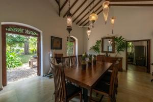 a dining room with a wooden table and chairs at MO River House Luxury Villa in Hikkaduwa