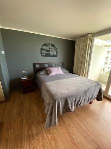 Dormitorio con cama con almohada rosa en Departamento condominio Laguna del Mar, en La Serena
