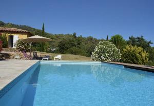 une grande piscine bleue avec une maison en arrière-plan dans l'établissement Villa Cabasse, à Cabasse