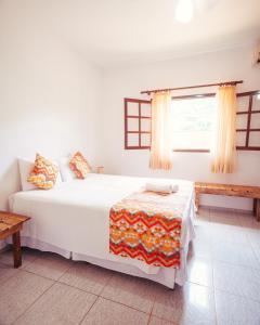 a bedroom with a white bed and a window at Pousada Flores do Lázaro in Ubatuba