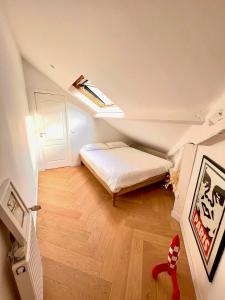 a small attic bedroom with a bed and a skylight at Maison d'architecte Triplex in Paris