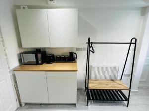 a kitchen with white cabinets and a counter with a microwave at Stylish studio in Milton Keynes