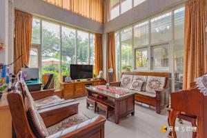 sala de estar con sofá, TV y ventanas en 苗栗公館聚福居民宿, en Miaoli