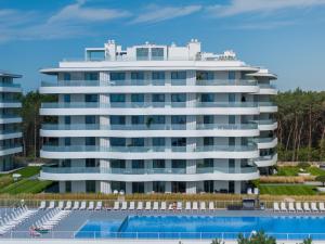 a large white building with a pool in front of it at SandLand - Rogowo Pearl in Rogowo