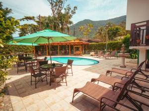 a patio with chairs and a pool with a table and umbrella at Pousada Flores do Lázaro in Ubatuba