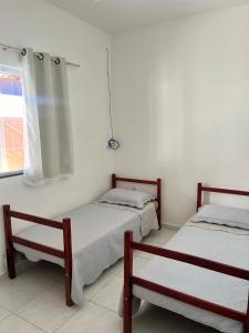 Cette chambre blanche dispose de 2 lits et d'une fenêtre. dans l'établissement Beach House Guriri - Casa de temporada, à São Mateus