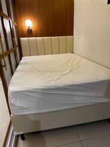 uma cama num quarto com lençóis brancos em Flat luxo Gravatá em Gravatá