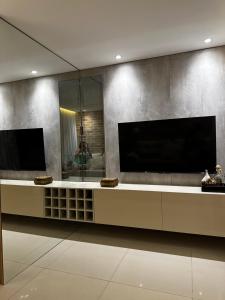 uma sala de estar com uma grande televisão na parede em Flat luxo Gravatá em Gravatá