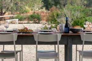 una mesa con copas y una botella de vino en VILLA DE LUXE AVEC PISCINE - TRULLO ULIVI al SOLE, en Francavilla Fontana