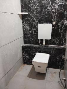 um WC branco numa casa de banho com uma parede preta em Smart living Opal em Indore