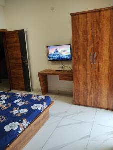 um quarto com uma cama e uma secretária com uma televisão em Smart living Opal em Indore