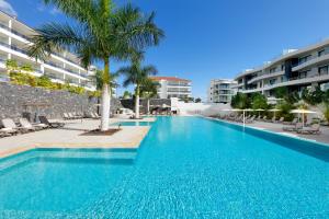 ein Pool mit einer Palme und einige Gebäude in der Unterkunft Marinell Collection Palm-Mar in Palm-mar