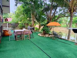 patio con tavolo, sedie e ombrellone di บาคัสโฮมลอร์ด a Haad Chao Samran