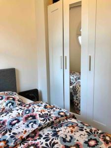 1 Schlafzimmer mit einem Bett mit Blumenbettdecke und einem Spiegel in der Unterkunft Flat in Choisy Le Roy, 6 min from Paris in Choisy-le-Roi