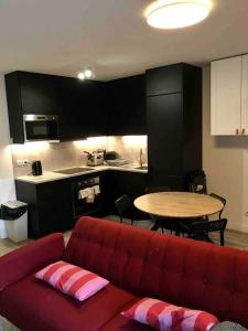 ein Wohnzimmer mit einem roten Sofa und einem Tisch in der Unterkunft Flat in Choisy Le Roy, 6 min from Paris in Choisy-le-Roi