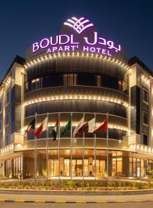 um edifício com bandeiras à sua frente à noite em Boudl Al Rawdah em Buraydah