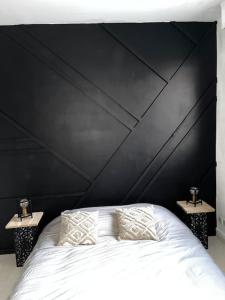 a bedroom with a large black headboard with two night stands at Appartement Cosy Goussainville - Aéroport CDG, Parc des expositions Villepinte, Astérix, JO 2024 in Goussainville