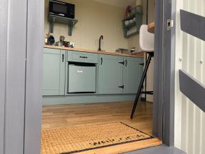 una cocina con armarios azules y una alfombra en el suelo en Burren Garden Glamping Hut, en Boston