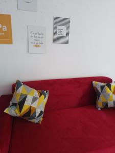Sofá rojo con 2 almohadas amarillas y negras en CactusStudio en Salvador