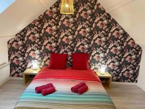 ein Schlafzimmer mit einem großen Bett mit zwei roten Kissen in der Unterkunft La Montbourgeoise in Montebourg