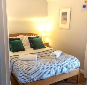 a bedroom with a bed with green pillows at Rosewall in St Ives
