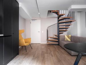 a living room with a couch and a spiral staircase at numa I Bloc Rooms & Apartments in Frankfurt/Main