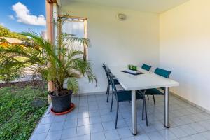 a table and chairs in a room with a plant at KawanNid Plage à 200m, Wifi, Clim, parking, Jardin Privé in Grand-Bourg
