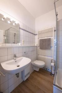 Baño blanco con lavabo y aseo en Haus Nordstrand FeWo Zingst, en Prerow