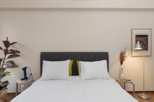 um quarto com uma cama grande com lençóis brancos e almofadas em Lovely Apartment in Exarcheia em Atenas