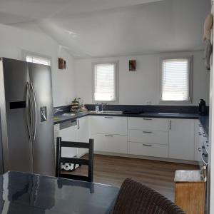 a kitchen with white cabinets and a stainless steel refrigerator at La désirée à Noirmoutier in Noirmoutier-en-l'lle