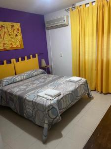 ルイデラにあるHostal y Apartamentos la Veredaのベッドルーム1室(黄色と紫の壁の大型ベッド1台付)
