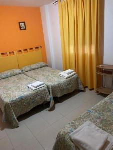 a hotel room with two beds and a yellow curtain at Hostal y Apartamentos la Vereda in Ruidera