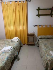 um quarto de hotel com duas camas e uma cortina amarela em Hostal y Apartamentos la Vereda em Ruidera