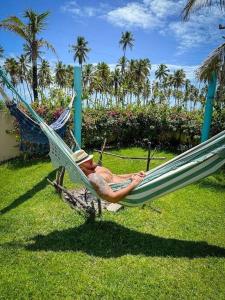 a man sitting in a hammock on the grass at Reserva do Paiva suites in Cabo de Santo Agostinho