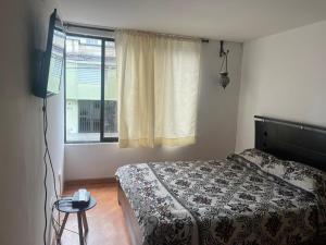 um quarto com uma cama e uma janela em Bhospedaje em Manizales