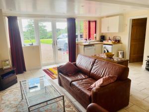 a living room with a brown leather couch and a table at Burraton Cob in Exeter