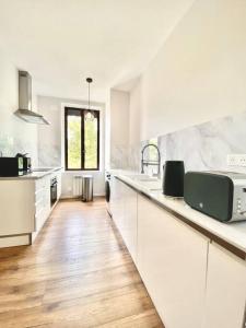 eine weiße Küche mit weißen Schränken und Holzböden in der Unterkunft Appartement complet chic et cosy in Sains-Richaumont