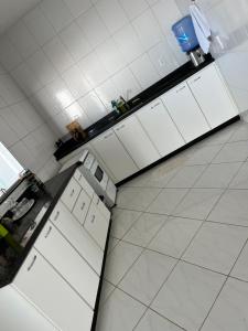 - une vue sur la cuisine avec des placards blancs dans l'établissement Beach House Guriri - Casa de temporada, à São Mateus