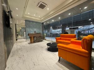 a lobby with two orange chairs and a table at Hotel Mumbai House, Malad in Mumbai